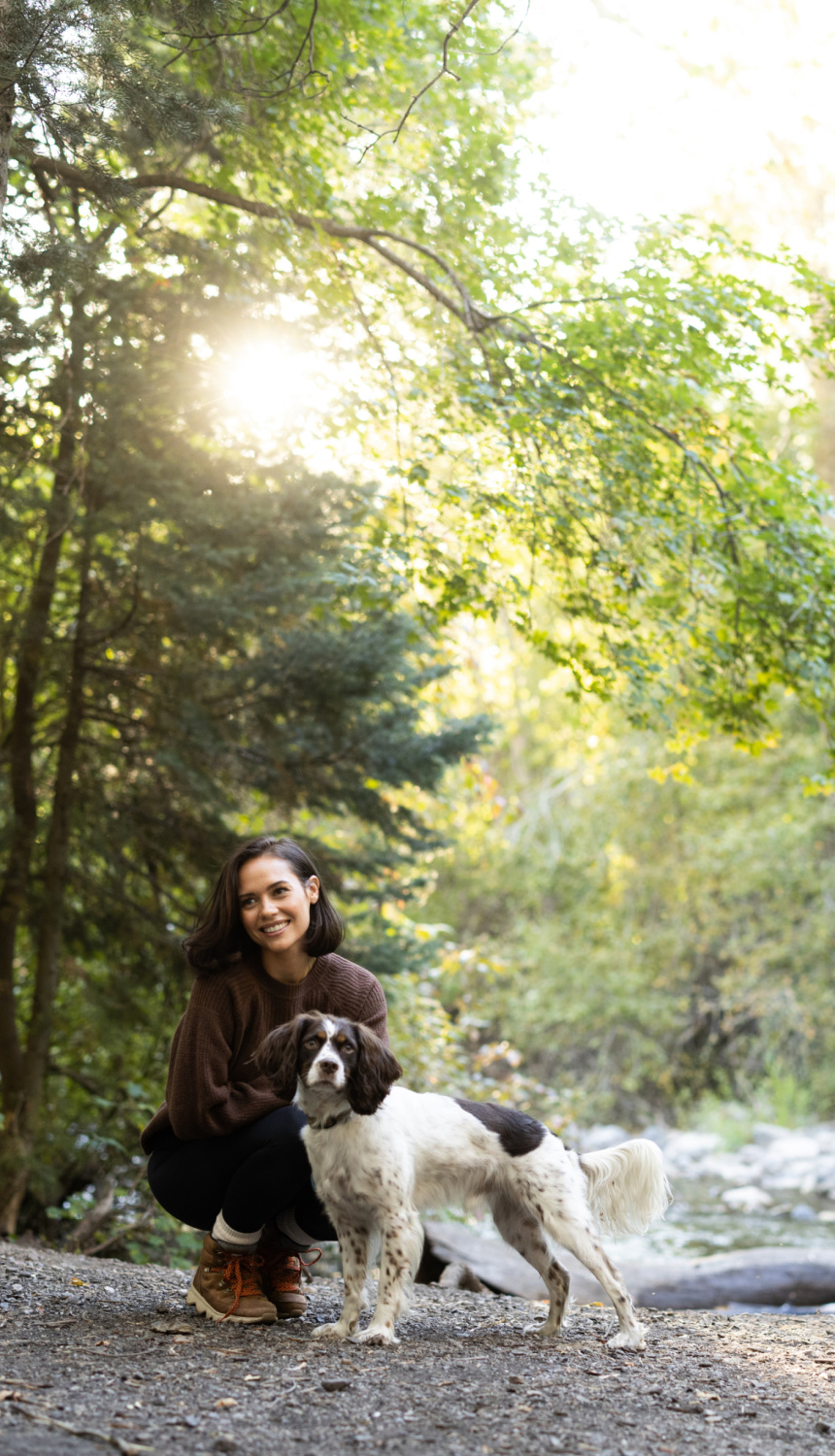 Woman kneeling with dog in woods