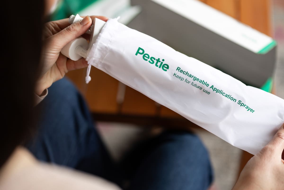 Pestie box with Pestie sprayer inside sitting on a garage shelf.