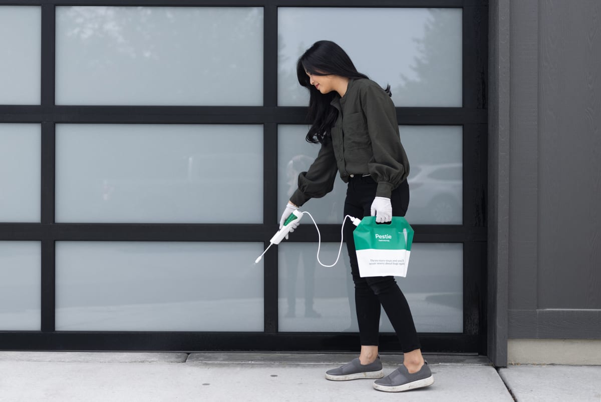 Man spraying Pestie on garage door opening.