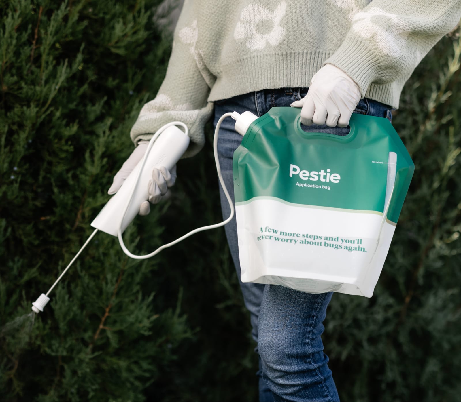 Woman spraying Pestie near ferns.