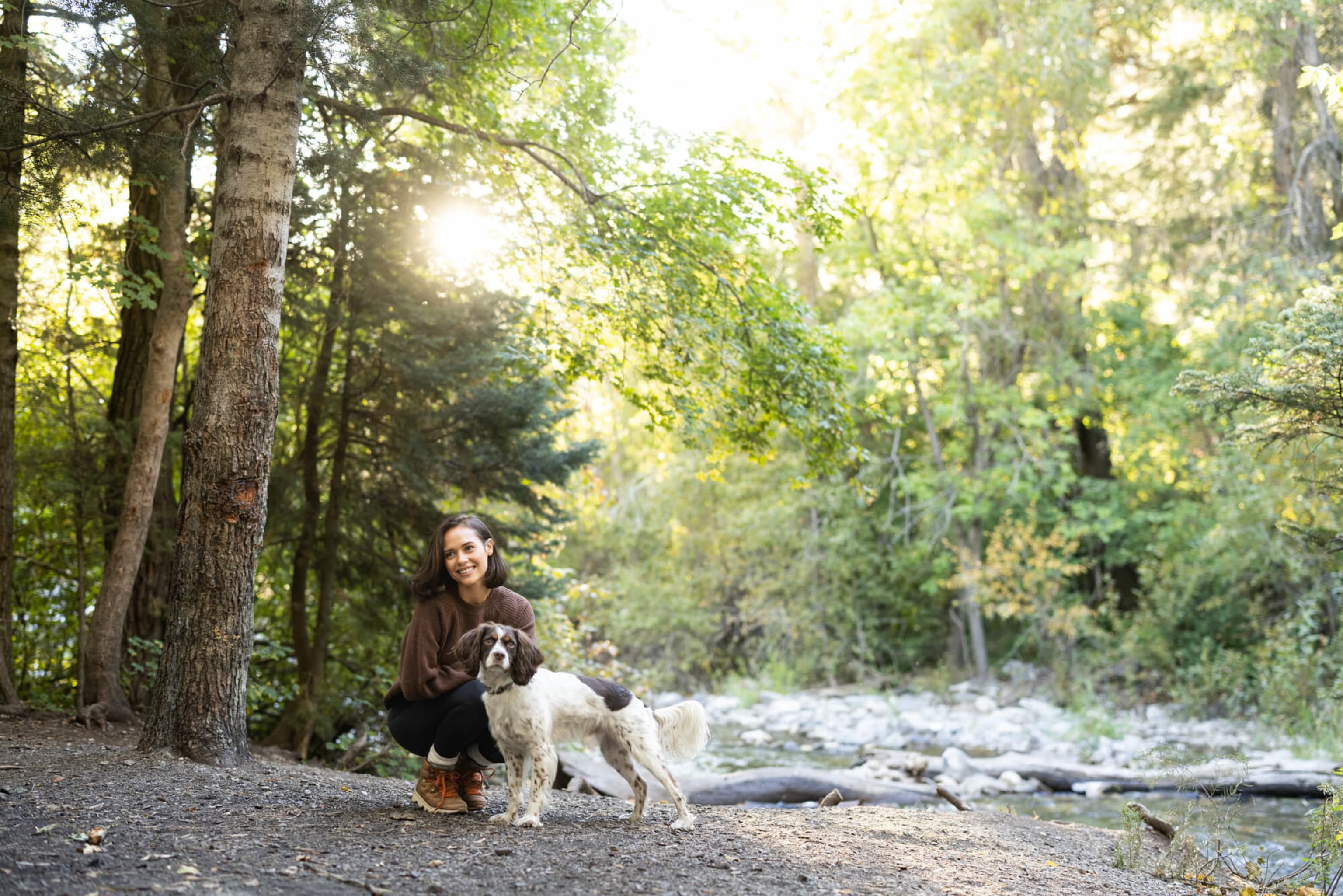 Woman kneeling with dog in woods