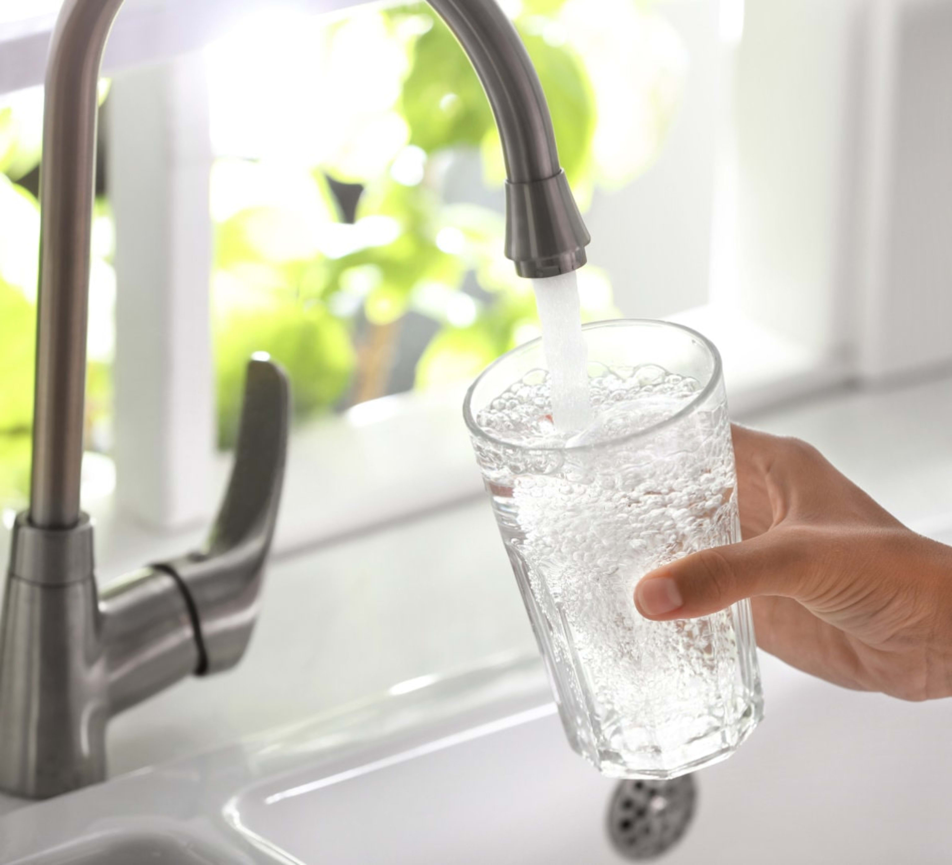 Filling up a glass cup with water in a sink