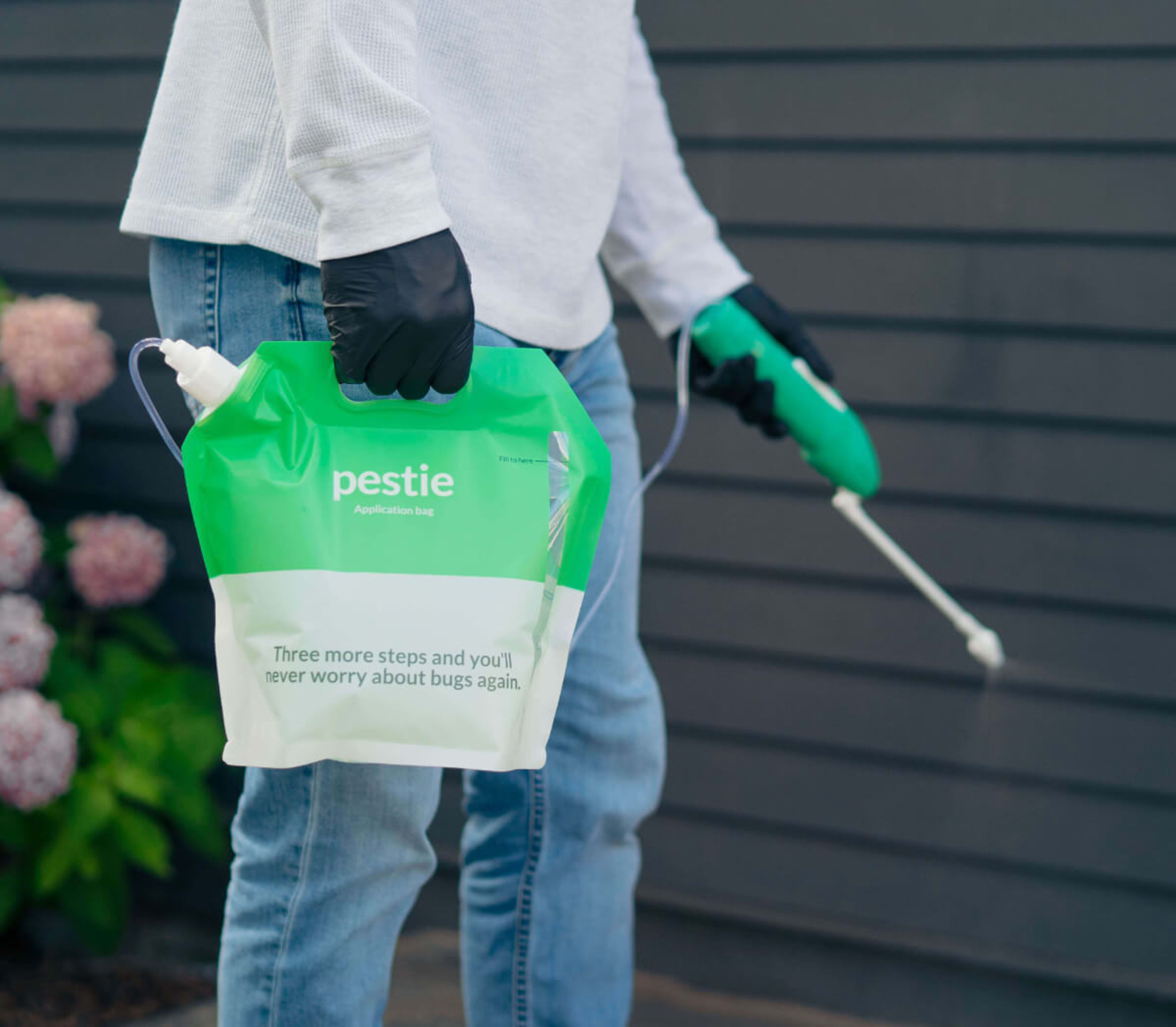 Man holding Pestie bag while applying on his house