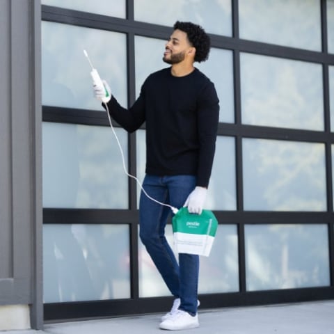Man spraying Pestie on garage door opening.