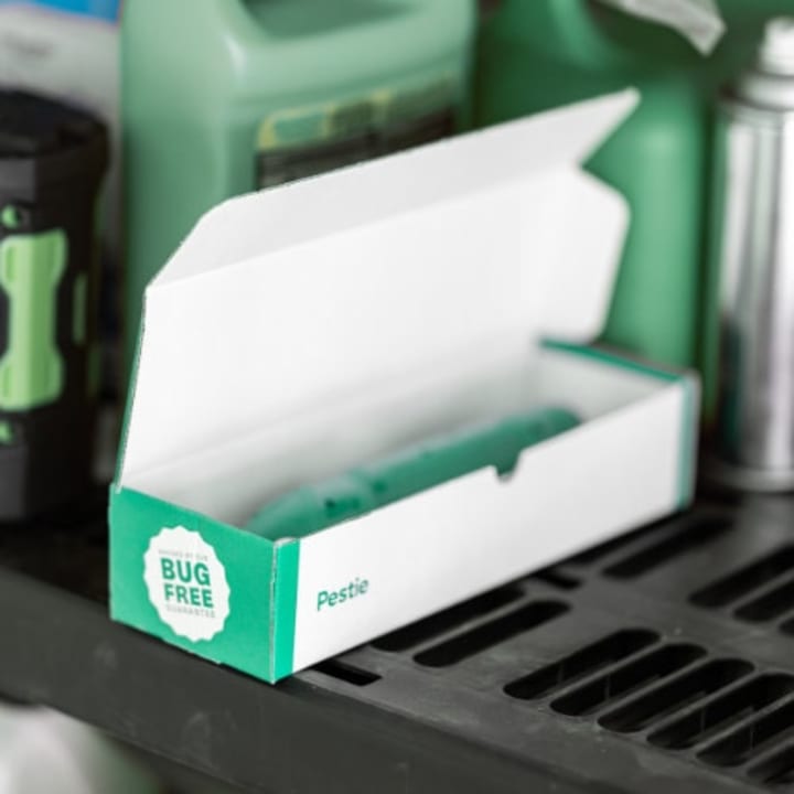 Pestie box with Pestie sprayer inside sitting on a garage shelf.