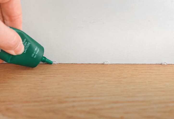 Ant gel bait being placed along a baseboard.