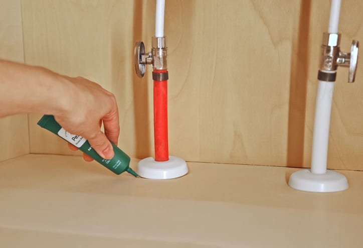 Ant gel bait being placed under a sink.