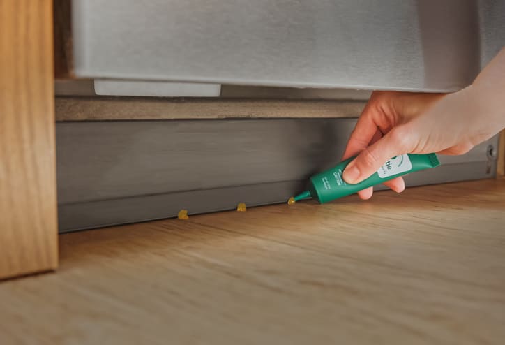Gel bait being placed near a large appliance.