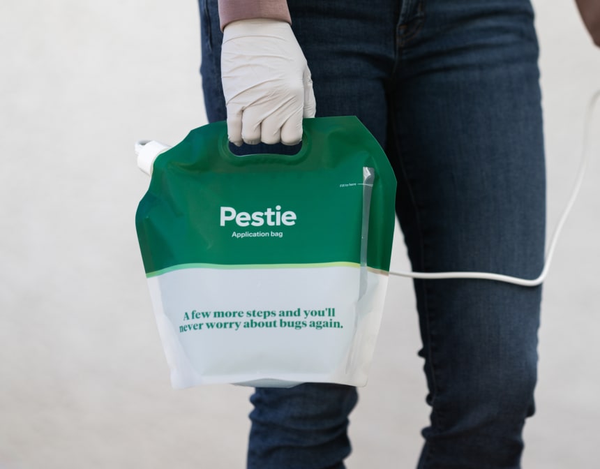 Woman spraying Pestie on a garage.