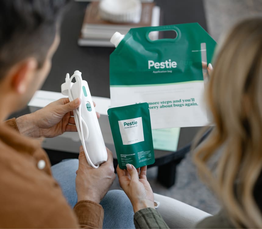 Woman spraying Pestie near ferns.